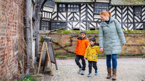 A family walking around the exterior of Little Moreton Hall, Cheshire